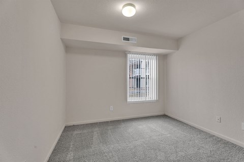 A room with a window and a grey carpet.