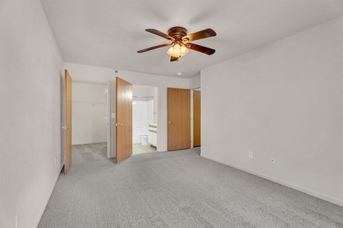 A room with a ceiling fan and carpeted floor.