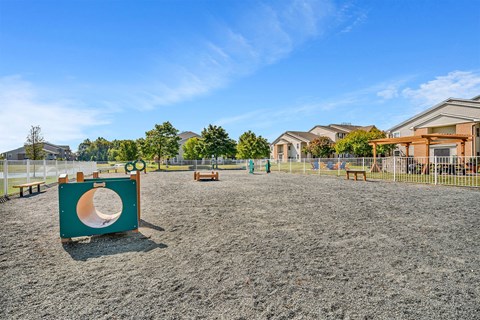A playground with a slide and sandbox in the foreground and houses in the background.