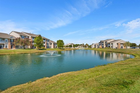 A serene lake surrounded by residential buildings under a clear blue sky.