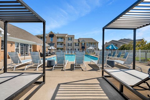 A pool surrounded by lounge chairs and umbrellas.