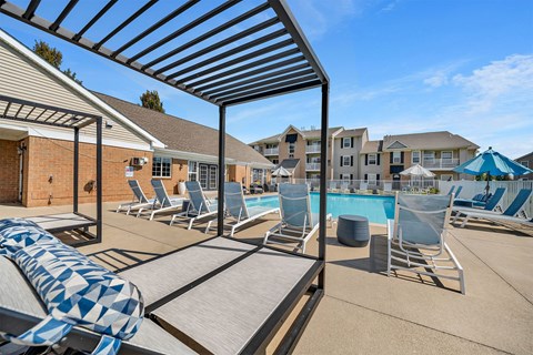 A pool area with sun loungers and a blue umbrella.