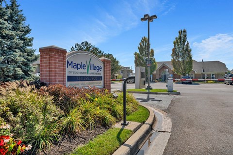 A sign for Maple Village in front of a building.