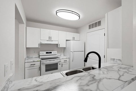 A kitchen with white cabinets and a marble countertop.