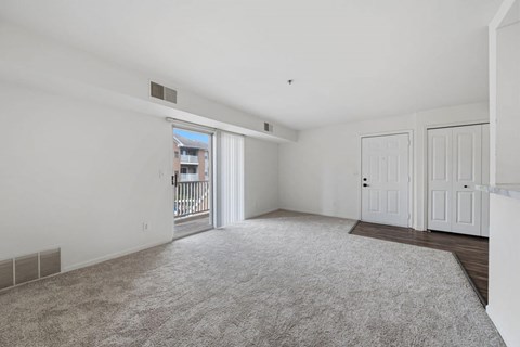 A spacious room with a carpeted floor and a sliding glass door leading to a balcony.