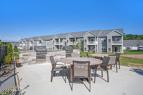 A patio with a table and chairs is in front of apartment buildings.