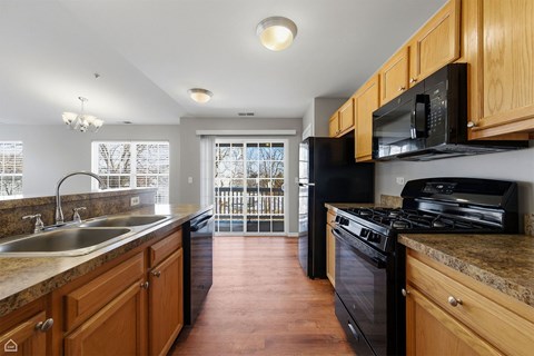 A kitchen with wooden cabinets and black appliances.