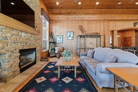 A living room with a stone fireplace and a rug with a floral pattern.