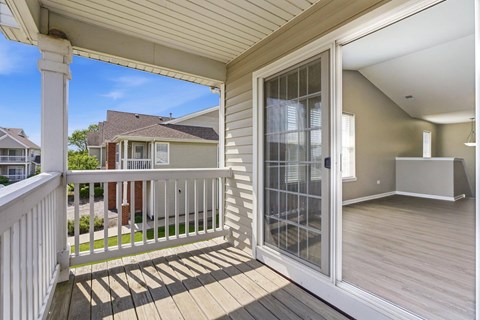A white screened door is open to a room with wood flooring.