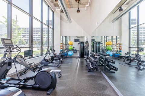 a gym with weights and cardio equipment and large windows