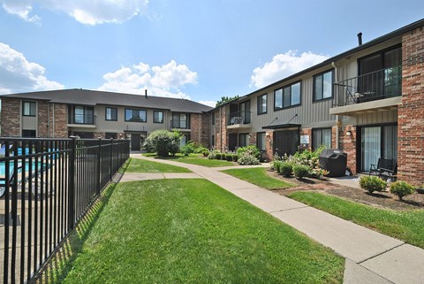A sunny day at a residential complex with a pool and green lawns.