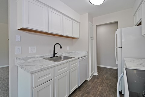 A kitchen with white cabinets and a marble countertop.