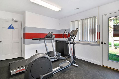 A home gym with a treadmill, exercise bike, and weights.