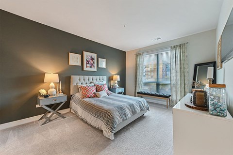 A bedroom with a large bed and a window with curtains.
