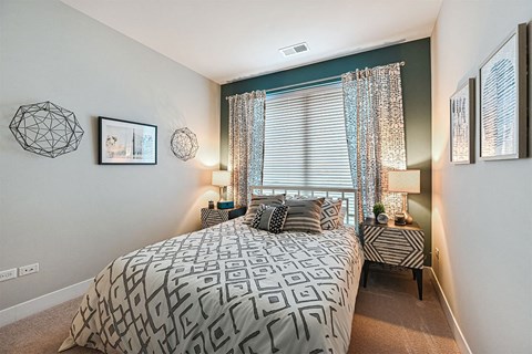 A bedroom with a large bed and a window with curtains.