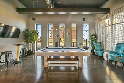 A room with a pool table and a bar area.