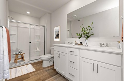 A white bathroom with a toilet, sink, and shower.