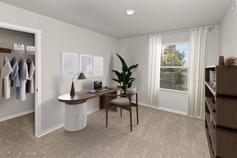 A room with a desk, chair, and a plant.