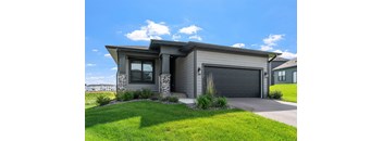 A modern house with a grey garage door and a stone pillar.