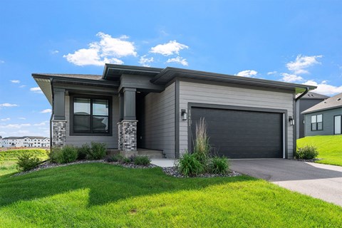 A modern house with a grey garage door and a stone pillar.