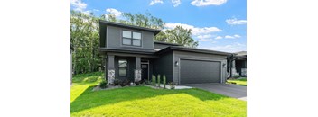 A modern house with a grey exterior and a black garage door.