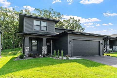 A modern house with a grey exterior and a black garage door.
