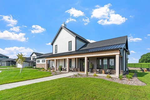 A modern house with a black roof and a large front porch.