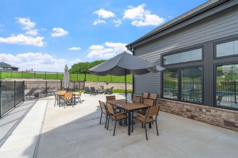 A patio with a table and chairs and a black umbrella.