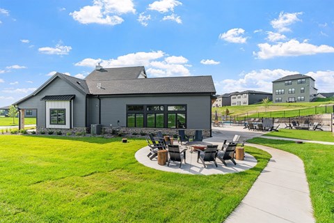A grey building with a sign that reads 1716 sits in a grassy field.