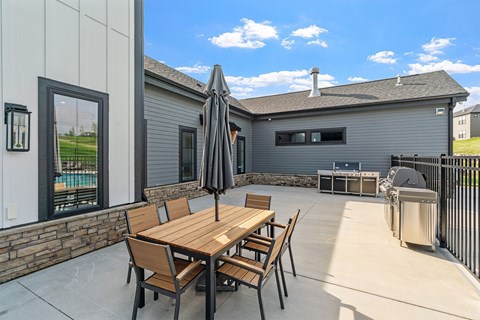 A patio with a table and chairs is set up outside a house.