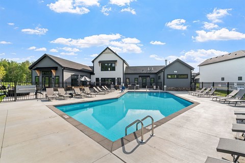 A swimming pool in front of a building with a sunny sky.