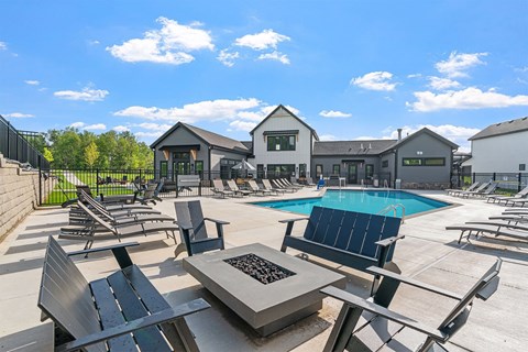 A sunny day at the pool with a fire pit in the middle.