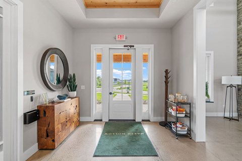 A white hallway with a green rug and a mirror on the wall.