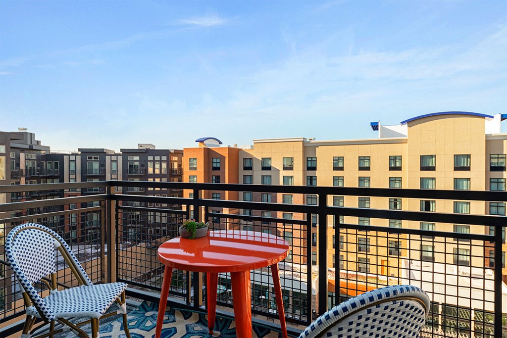 a patio with a red table and chairs on a balcony