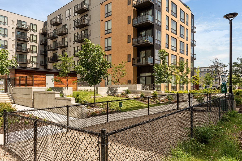an apartment complex with a fenced in yard and a chain link fence