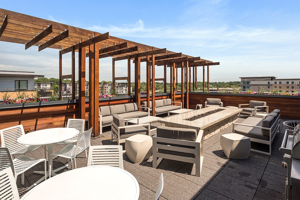a rooftop patio with tables and chairs and a fire pit