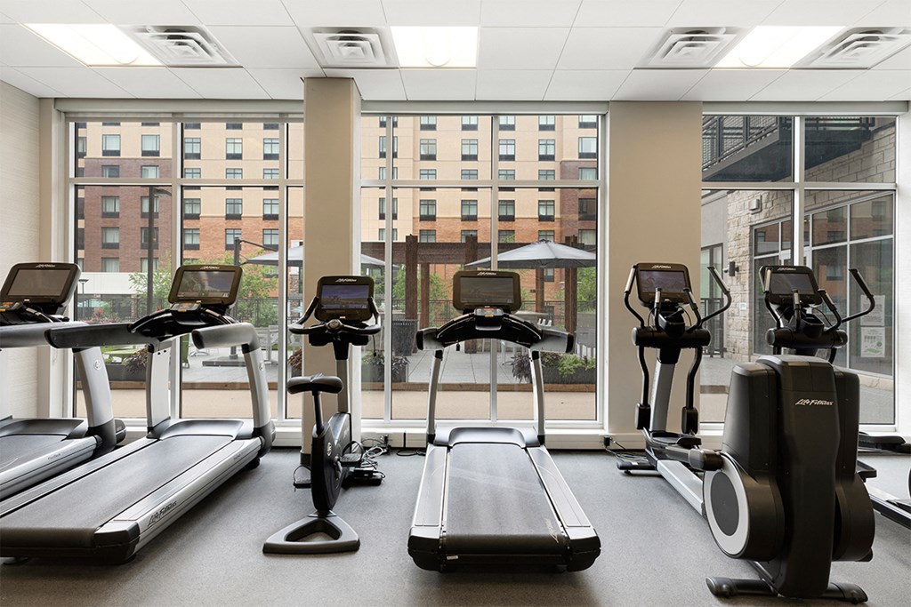a gym with cardio machines and a view of the window