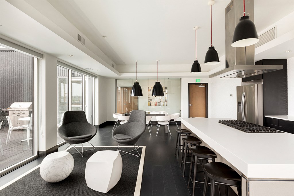 a kitchen and living room with a white counter and chairs