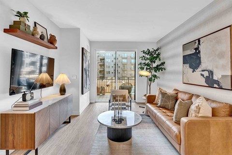 A living room with a brown couch, a coffee table, and a painting on the wall.