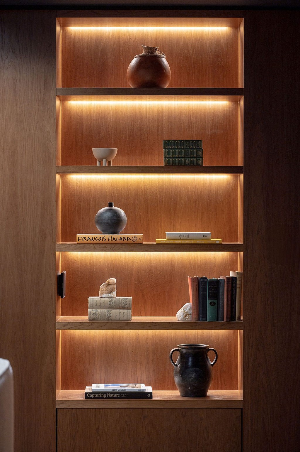 A shelf with books and vases on it.