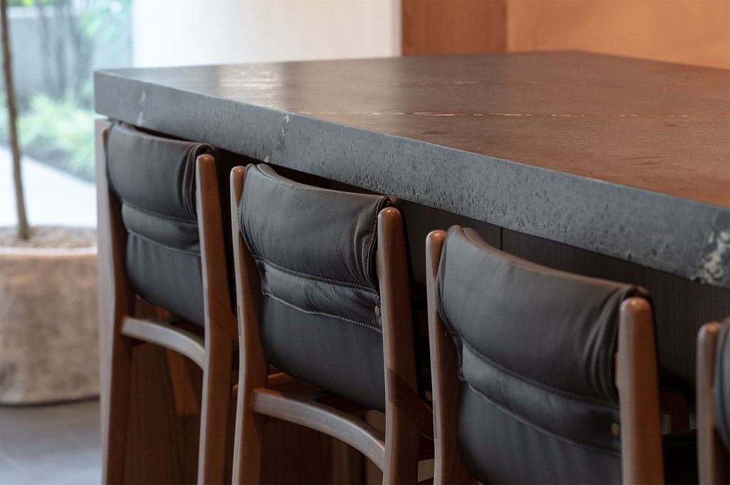 A long table with four chairs and a grey cushion is in the foreground.