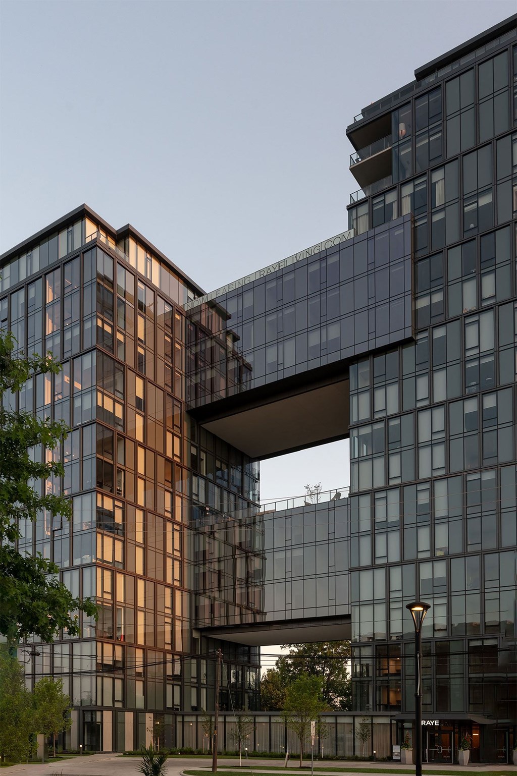 Two modern glass buildings are connected by a bridge.