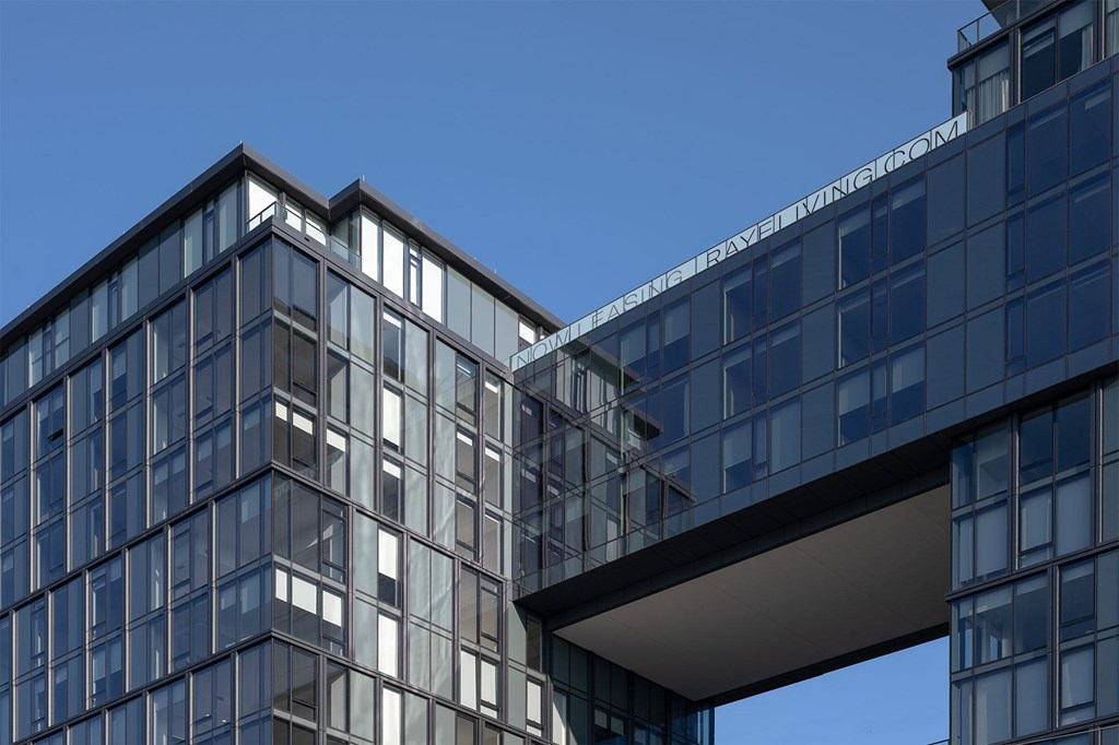 A modern glass building with a clear blue sky in the background.