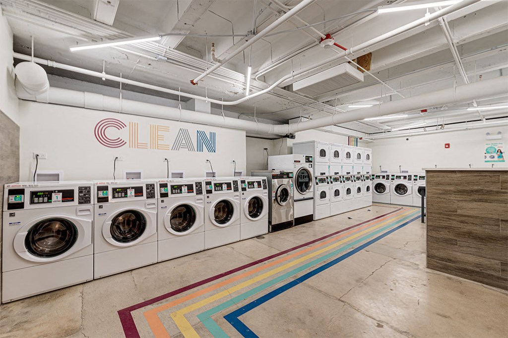 a laundromat with a row of washing machines and a wall of dryers