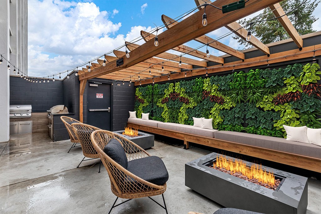 a patio with a fire pit and a green wall