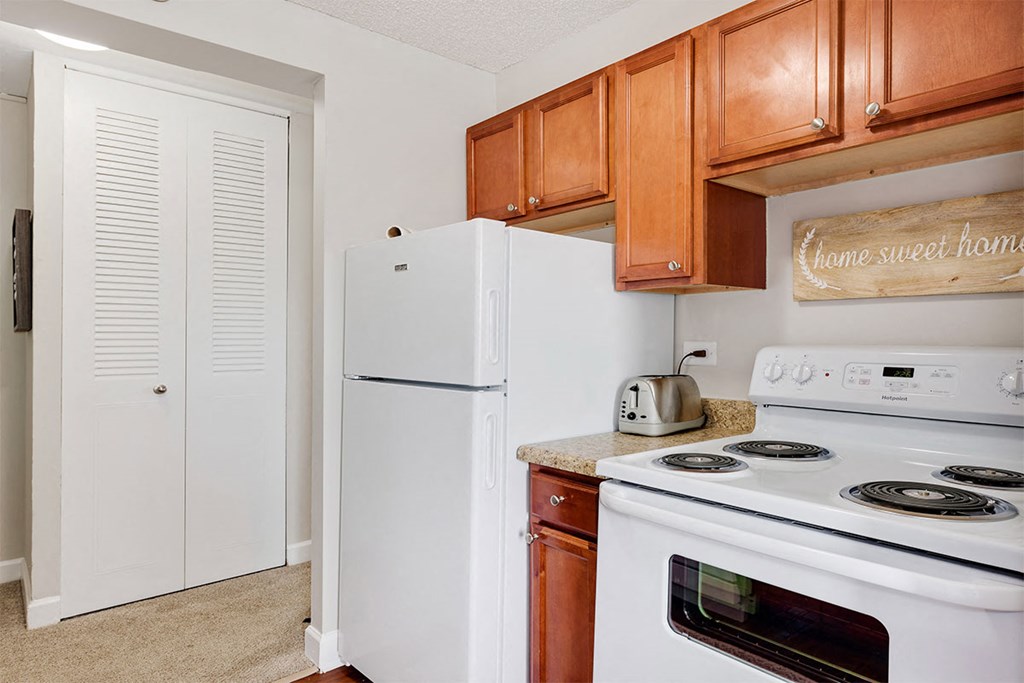 a kitchen with white appliances and wooden cabinets and a refrigerator