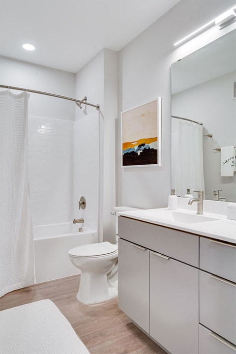 A white bathroom with a toilet, sink, and shower.