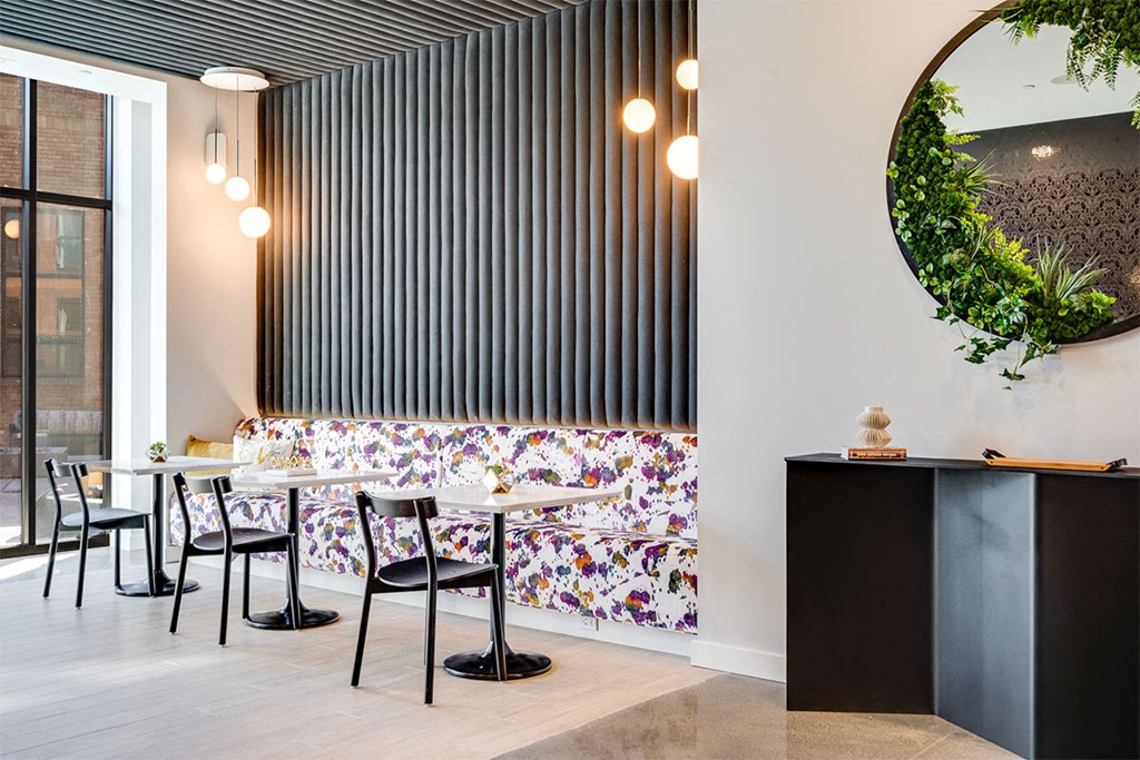 A black and white striped wall with a round mirror and a green plant on top.