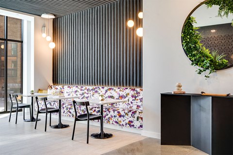 A black and white striped wall with a round mirror and a green plant on top.