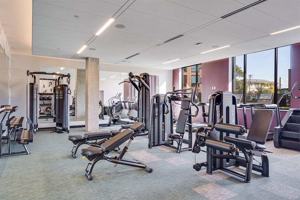 A gym with a variety of equipment including treadmills, weights, and exercise machines.